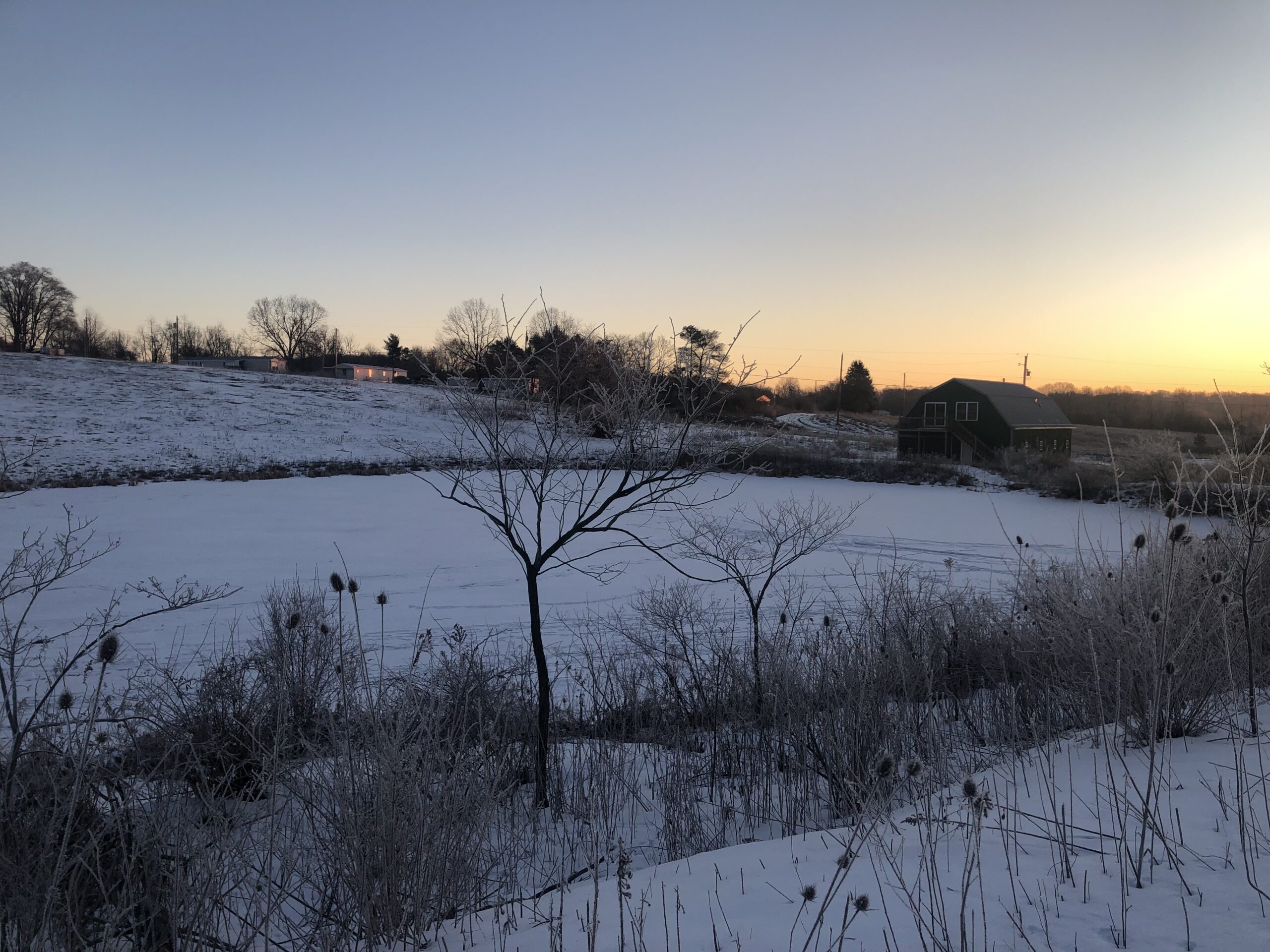 Frozen pond, barn, and trees in snow