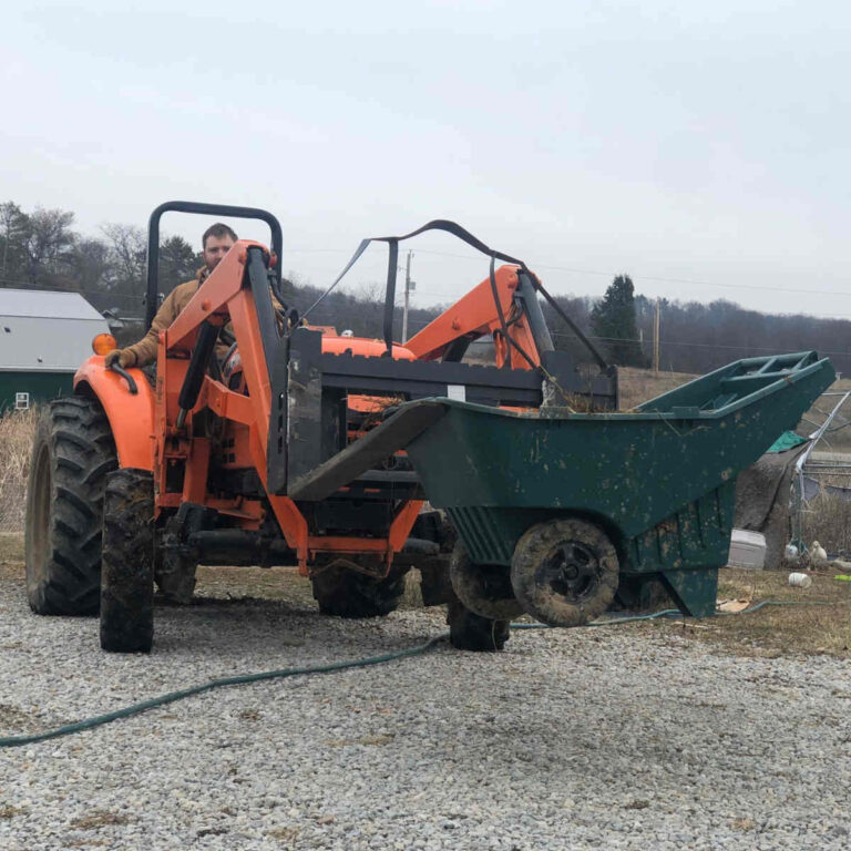 Compact orange tractor holding wheelbarrow