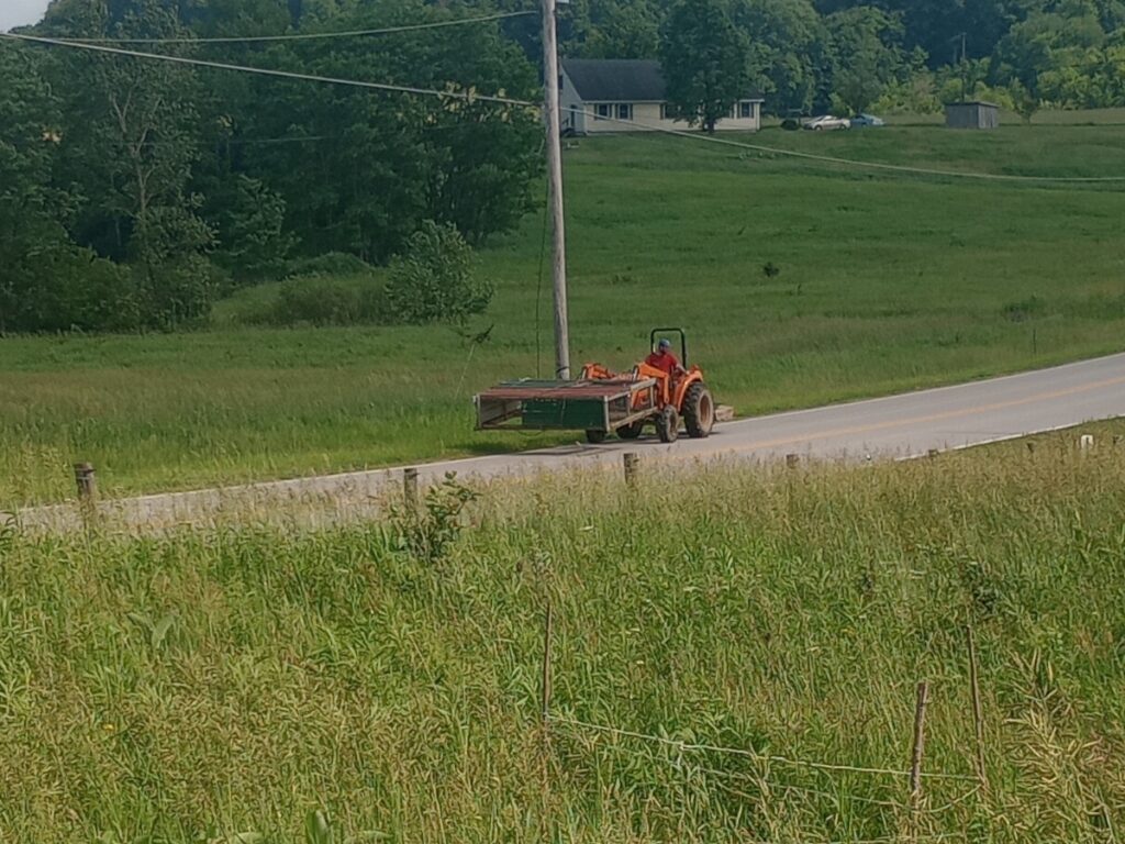 Tractor carrying chicken tractor down road
